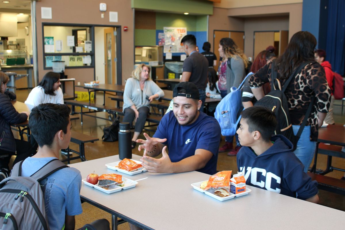 Mentor talks to students in a cafeteria