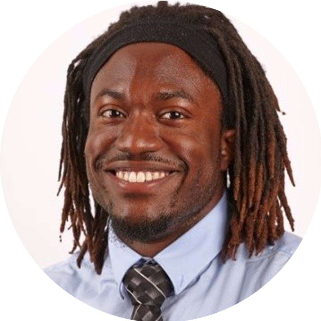 Mike Browne smiling with hair in dreads and a blue button up with tie