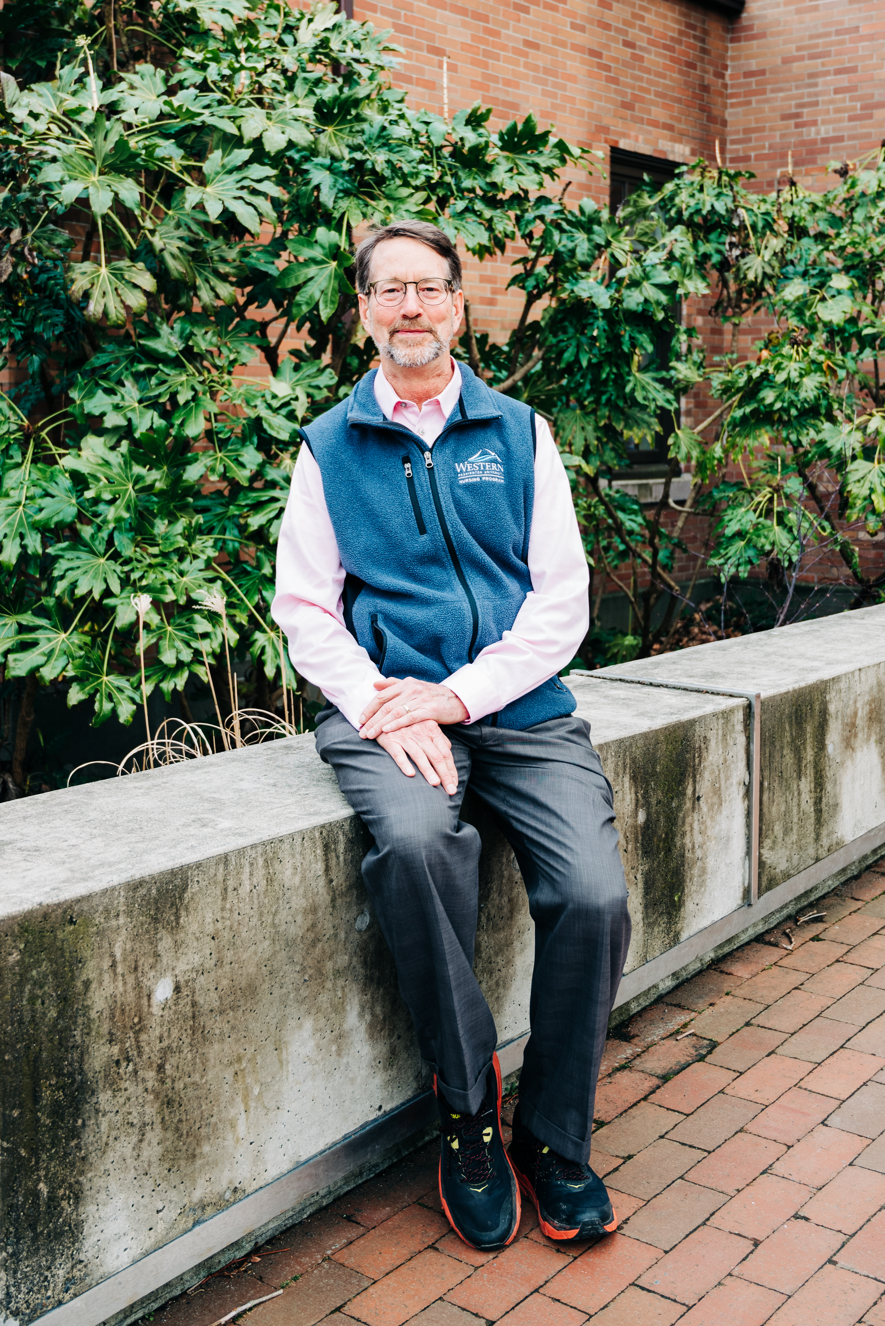 Bill Lonneman sitting on the concrete railing outside of Miller Hall in WWU Red Square