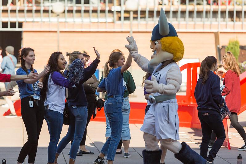 A group of students give high fives to Victor Viking Mascot