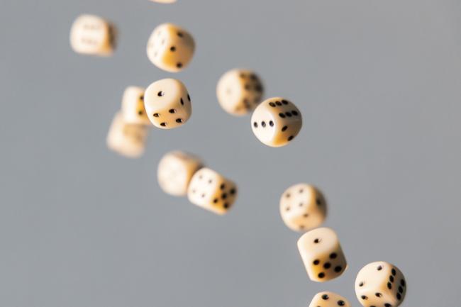 A handful of tan dice falling through the air