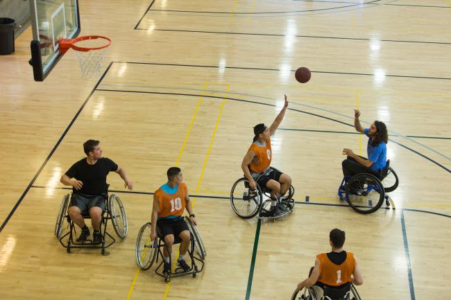 Five students in wheelchairs play basketball in the gym