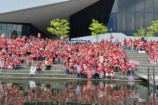 Large group of WEA members sitting in matching red shirts smiling in a large group on a set of steps