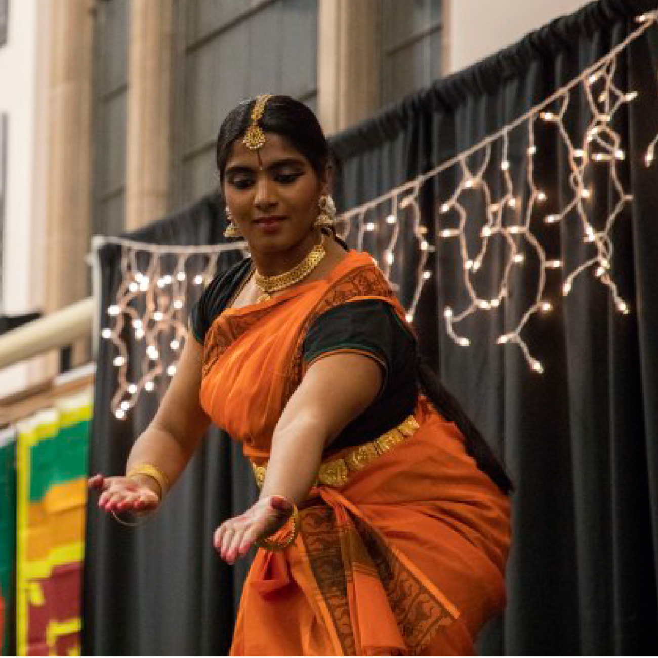 A South Asian dancer in traditional clothing performing on a stage
