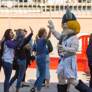 A group of students give high fives to Victor Viking Mascot