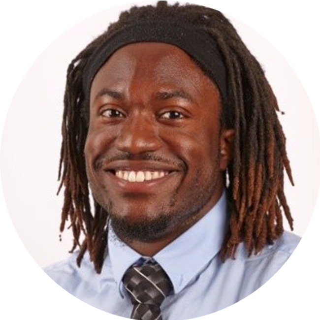 Mike Browne smiling with hair in dreads and a blue button up with tie