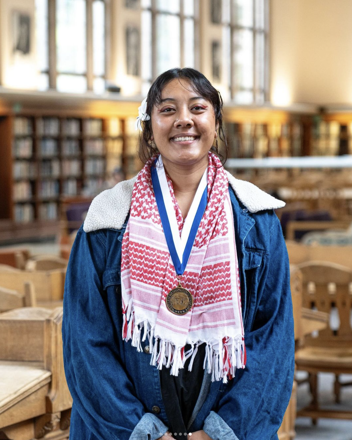 Meilani Wilson in a graduation robe standing for a portrait in Wilson Library wearing the Presidential Scholar medal around their neck
